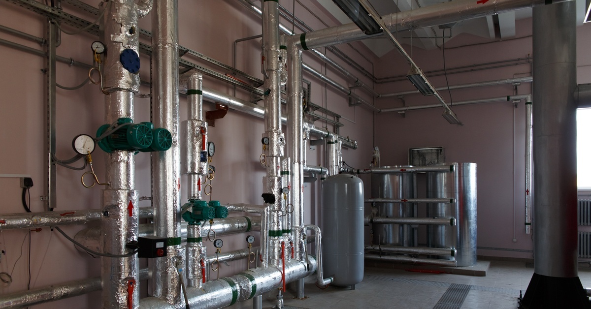 How To Avoid Sediment Buildup in Commercial Water Heaters A massive commercial space containing a water heater and many metal pipes that spread all over the wall and ceiling.