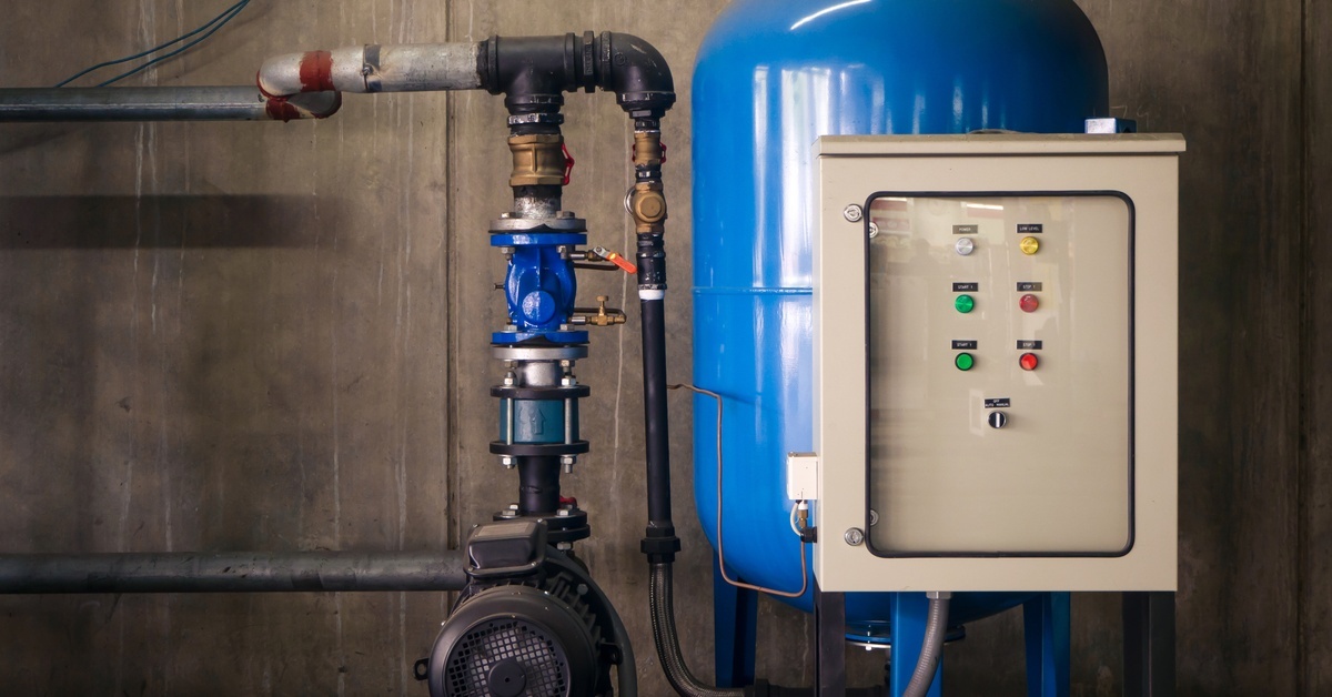 A small blue booster pump is connected to a large blue water tank via piping to improve water pressure.